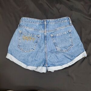 Classic blue denim women's shorts that say "HAPPY" on the back left pocket.